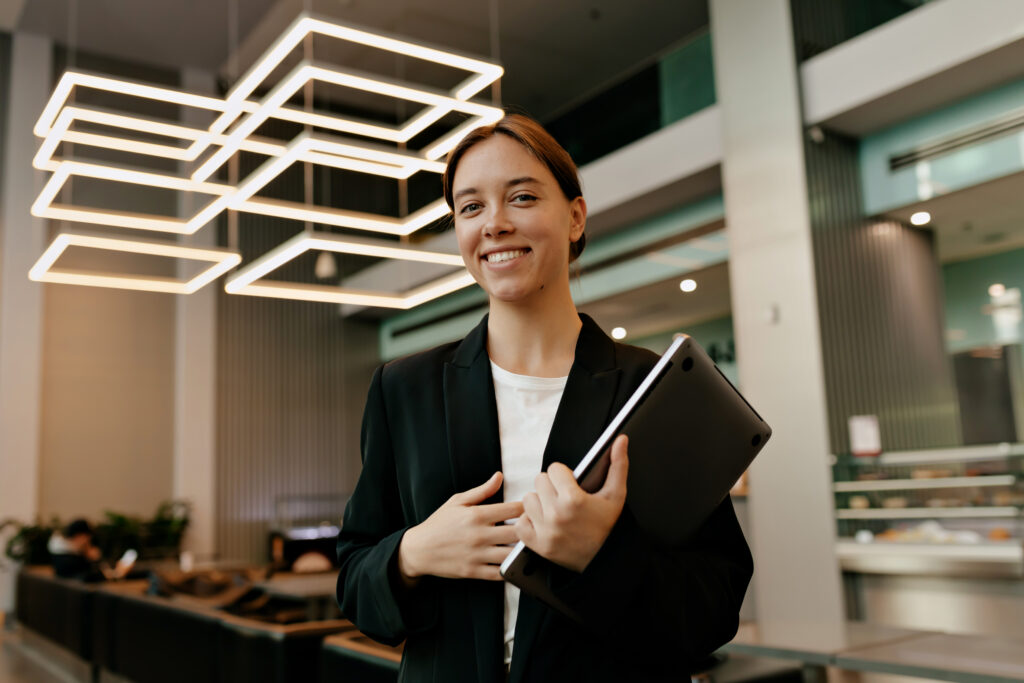 wonderful stylish business woman suit is holding laptop smiling camera